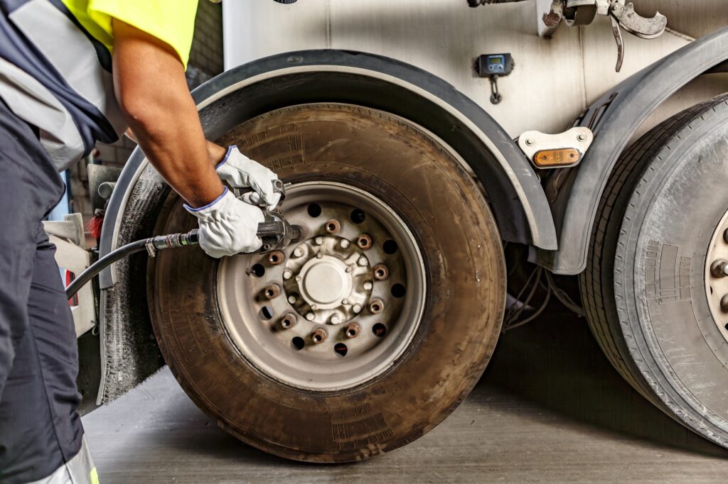 Crop mechanic tightening wheel of truck in workshop